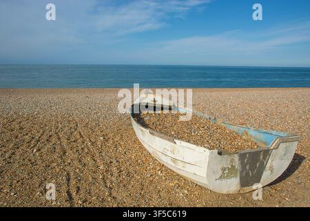 Verlassenes Fischerboot, gefüllt mit Strandkies, gestrandet am Strand von Seaford Stockfoto