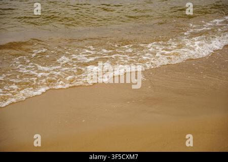 Sanfte weiße Meeresbrandung wäscht über eine goldene Sandküste unter natürlichem Tageslicht am Strand, Küstenwellenbewegung, Küstentexturen, ruhige Strandlandschaft, marine Geologie Stockfoto
