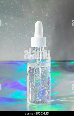 Klares Hyaluronsäure-Serum in Tropfflasche mit irisierendem Hintergrund für Hautpflege und Schönheit Stockfoto