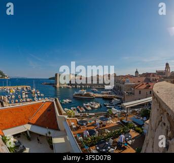 Dubrovnik, Kroatien – 14. September 2023: Das Personal bereitet den Außenbereich eines Restaurants vor, das mit Blick auf den Hafen und die historische Stadtmauer liegt. Stockfoto