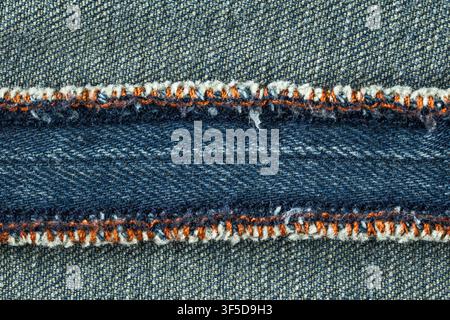 Blauer Denimstoff mit einer gelben Naht, der einen vielseitigen Textilhintergrund bildet Stockfoto