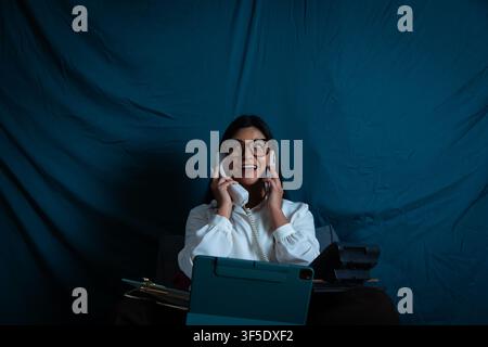 Frau, die Multitasking betreibt und gleichzeitig an zwei Telefonen telefoniert Stockfoto