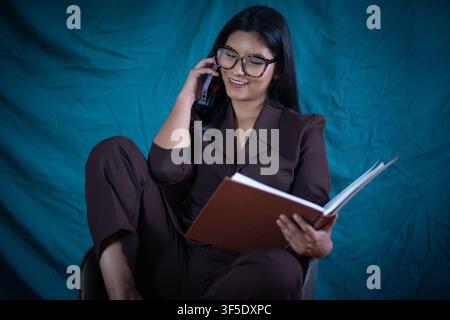 Geschäftsfrau telefoniert, liest ein Buch und multitaskt Stockfoto