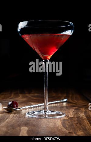 Nahaufnahme eines Whiskey Manhattan, serviert mit einer Kirsche auf einem rustikalen Holzgrund Stockfoto