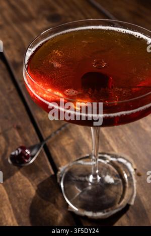 Nahaufnahme eines Tropfens auf einem Whiskey Manhattan, serviert auf einem rustikalen Holzuntergrund Stockfoto