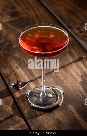 Nahaufnahme eines Tropfens auf einem Whiskey Manhattan, serviert auf einem rustikalen Holzuntergrund Stockfoto