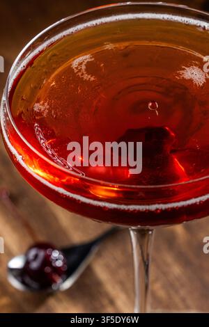 Nahaufnahme eines Tropfens auf einem Whiskey Manhattan, serviert auf einem rustikalen Holzuntergrund Stockfoto
