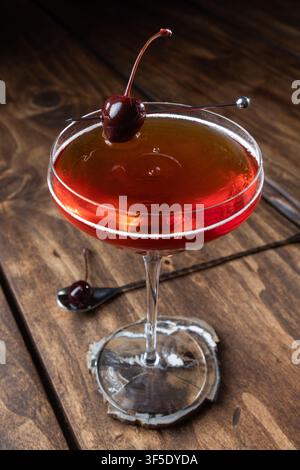 Nahaufnahme eines Tropfens auf einem Whiskey Manhattan, serviert auf einem rustikalen Holzuntergrund Stockfoto