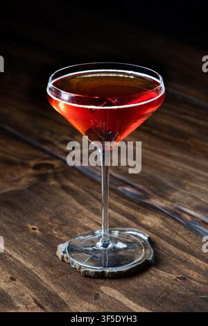 Nahaufnahme eines Whiskey Manhattan, serviert mit einer Kirsche auf einem rustikalen Holzgrund Stockfoto