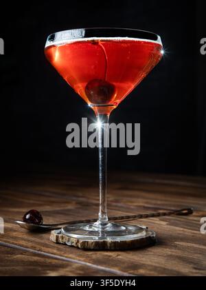 Nahaufnahme eines Whiskey Manhattan, serviert mit einer Kirsche auf einem rustikalen Holzgrund Stockfoto