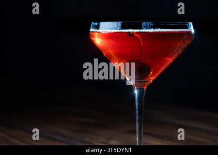 Nahaufnahme eines Whiskey Manhattan, serviert mit einer Kirsche auf einem rustikalen Holzgrund Stockfoto
