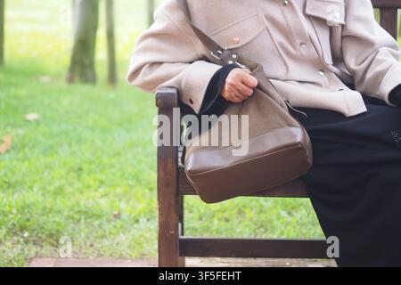 junge Frau sitzt auf einer Bank mit einer Tasche in einem Park Stockfoto