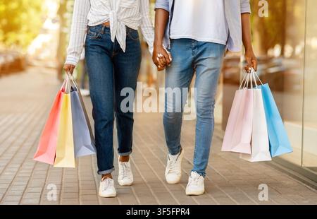 Lifestyle-Shopping. afroamerikanischer Mann und Frau mit Papiertüten, die die Straße hinunter laufen Stockfoto