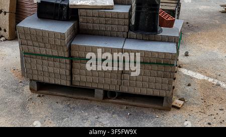 Gestapelte Bordsteine warten auf die Installation für Straßenreparaturarbeiten auf einer Baustelle an einem sonnigen Tag. Die Anordnung zeigt organisierte Materialien, die bereit sind Stockfoto