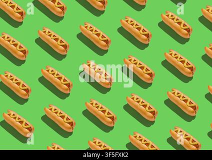 Viele klassische Hotdogs mit Senfsauce auf grünem Hintergrund, kreatives Muster Stockfoto