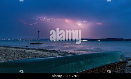 Dramatisches Langzeitfoto eines Blitzes, der sich über den Abendhimmel über dem Bodensee (Bodensee), Deutschland, verzweigt und die Klosteranlage beleuchtet Stockfoto