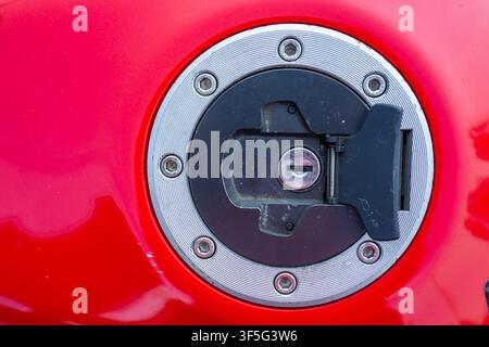 Roter Kraftstoffdeckel mit silbernem Rand und schwarzem Verschluss. Nahaufnahme zeigt Schlüsselloch und Verriegelungsmechanismus. Saubere, scharfe Fokussierung hebt mechanische Details hervor. Ideal Stockfoto