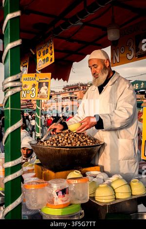 Wunderschöne Abendansicht eines Kochs, der frische Schnecken an Touristen und Einheimische auf dem Jemaa el-Fnaa-Platz im Medina-Viertel von Marrakech, Marokko, verkauft Stockfoto