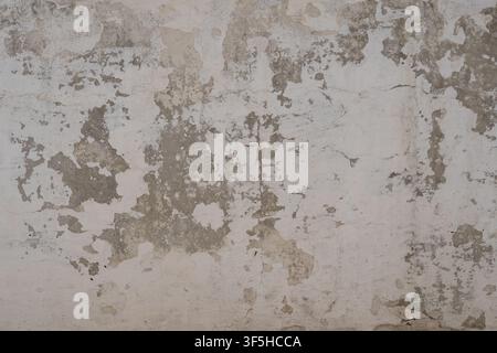 Alte Betonwand mit abblätterndem Putz und rissiger Oberfläche, die eine realistische Grunge-Textur für Design- und architektonische Hintergründe erzeugt. Stockfoto
