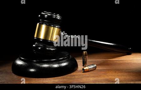 Zwei Handfeuerpatronen auf einem Tisch mit einem Richter-Hammer in einer Waffenentscheidung mit Platz für Kopie dahinter. Stockfoto