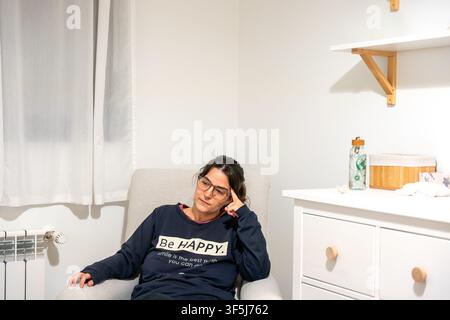 Frau, die Stress erlebt, sitzt auf einem Stuhl und denkt Stockfoto