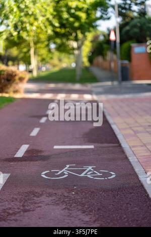 Fahrradsymbol auf einem roten städtischen Fahrradweg neben einem gepflasterten Fußgängerweg gemalt Stockfoto