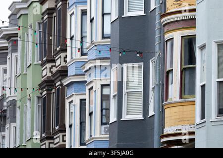 Nahaufnahme von farbenfrohen viktorianischen Stadthausfassaden mit Erkerfenstern und festlichen Lichterketten, die klassische Wohnarchitektur in San F zeigen Stockfoto