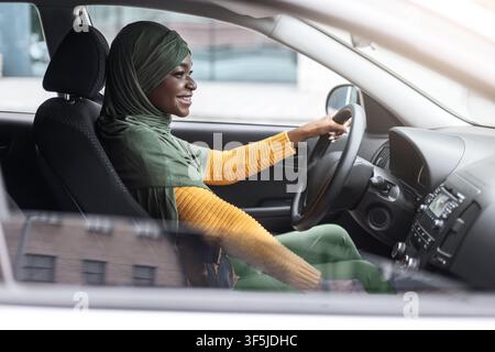 Selbstbewusst Schwarz Muslim Weiblich In Hijab Genießen Auto Fahren In Stadt Stockfoto