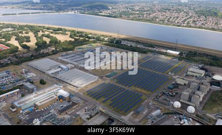 Luftaufnahme einer großen Kläranlage mit Solarpanelen, Sedimentationstanks und Industriegebäuden neben einem Reservoir und suburbanem Land Stockfoto