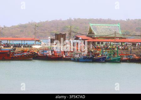 Bunte Holzfischerboote, die Seite an Seite an einem Küstenpier in einem thailändischen Fischerdorfhafen festgemacht sind. Stockfoto