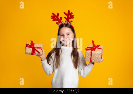 Kindheit, Weihnachten und Stimmung. Lächelndes Kind, das zwei Geschenke in ihren Händen hält Stockfoto