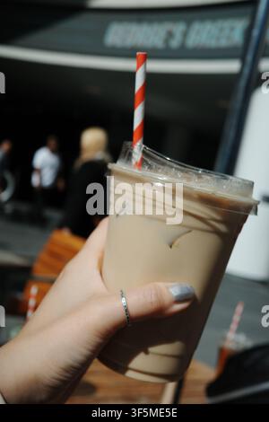 Hand, die ein Eiskaffee-Getränk mit einem gestreiften Strohhalm im Freien hält, Kalifornien Stockfoto