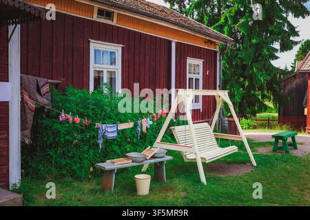 Kleidung und Bettwäsche trocknen im Hinterhof, und ein Wäschekorb steht daneben auf dem Rasen. Stockfoto