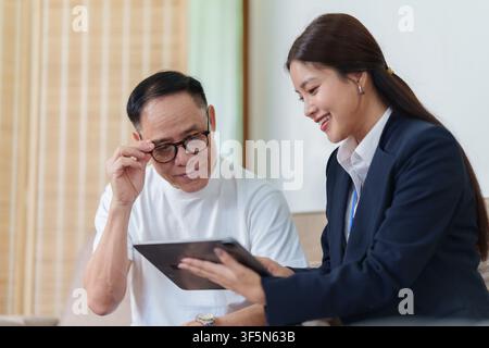 Asiatischer Senior überprüft digitale Dokumente auf einem Tablet mit einem Versicherungsagenten Stockfoto