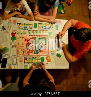 Familie und Freunde spielen gemeinsam zu Hause ein Brettspiel während eines gemütlichen Spieleabends, Ansicht von oben Stockfoto