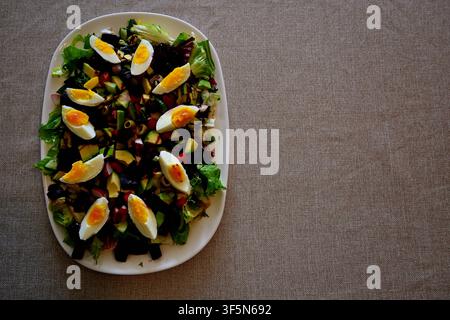 Frischer gemischter Gemüsesalat mit geschnittenen hartgekochten Eiern auf weißem Teller, Ansicht von oben. Stockfoto