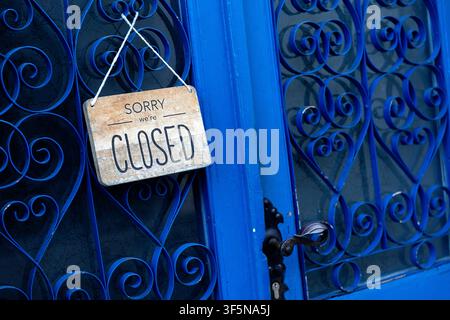 Schließschild an einer blauen hölzernen Restaurant-Eingangstür mit dekorativen Eisengittern über Glasplatten, in der historischen Stadt Kobarid, Slowenien. Stockfoto