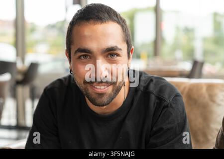 Junger Mann lächelt und schaut in die Kamera im Innenraum Stockfoto