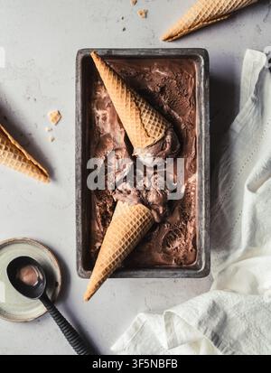 Flat Lay von Schokoladeneis mit Zuckerkegeln auf weißer Theke Stockfoto