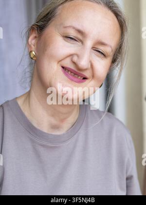 Frau lacht freudig mit geschlossenen Augen in einem Nahaufnahme-Porträt. Konzept von Zufriedenheit und kleinen Erfolgen nach einem erfolgreichen DIY-Projekt. Stockfoto