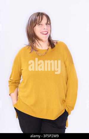 Jess Phillips posiert in einem hellen Innenraum. Sie hat langes Haar und trägt einen gelben Pullover sowie eine schwarze Hose. Der Fokus liegt auf ihrem Lächeln und Stockfoto