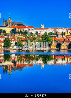 Prag-Burg und St.-Veits-Dom spiegeln sich in der Moldau zur goldenen Stunde mit historischer Stadtsilhouette und roten Dächern, vertikaler Hintergrund Stockfoto