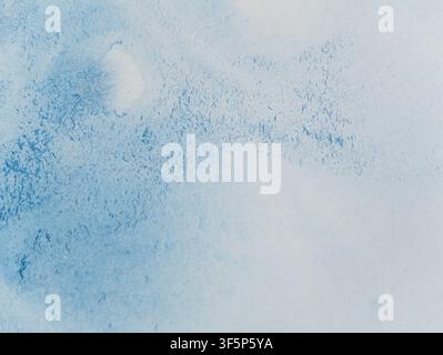Blaue Aquarellfarbe vermischt sich auf Papier. Helle blaue Pigmente verteilen sich natürlich über das Papier und erzeugen ein lebendiges freies Muster. Stockfoto