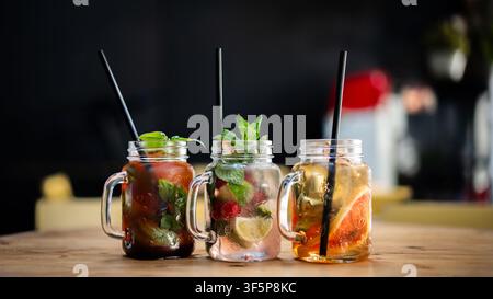 Nahaufnahme von drei Gläsern mit verschiedenen Eistees mit Früchten und Minze. Stockfoto