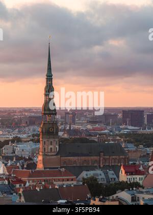 Drohnenflug über die Turmspitze der St.-Petri-Kirche in der Altstadt von Riga bei Dämmerung Stockfoto