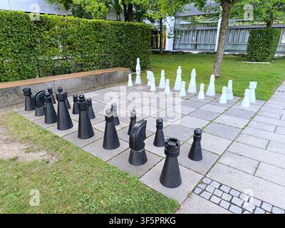 Riesiges Schachspiel im Freien mit großen schwarzen und weißen Figuren auf einem Gartenschachbrett Stockfoto