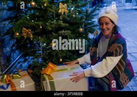 Glückliche Frau bereitet Geschenke unter dem Weihnachtsbaum vor Stockfoto