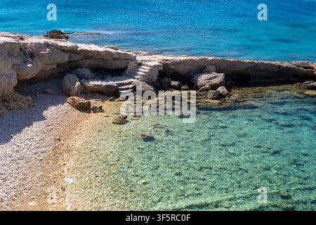 Felsige Küste mit Kalksteinformationen und klarem flachem Wasser in Koufonisia, Griechenland Stockfoto