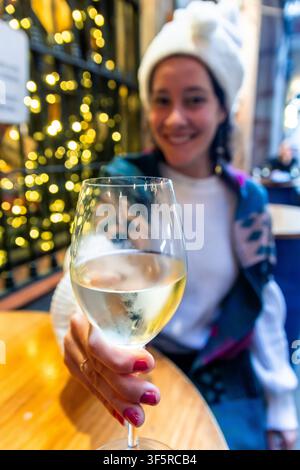 Frau genießt Weißwein und feiert die Weihnachtseinkäufe Stockfoto
