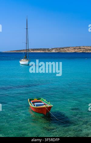 Rotes Fischerboot und weißes Segelboot, die in flachem türkisfarbenem Wasser vor Anker liegen, Koufonisia, Griechenland Stockfoto